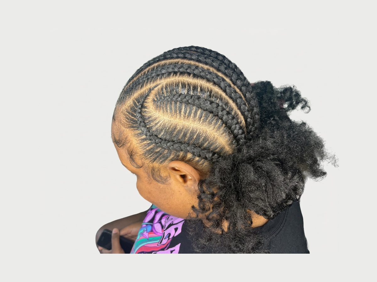 Full head view of curved stitch cornrows gathered into a curly ponytail