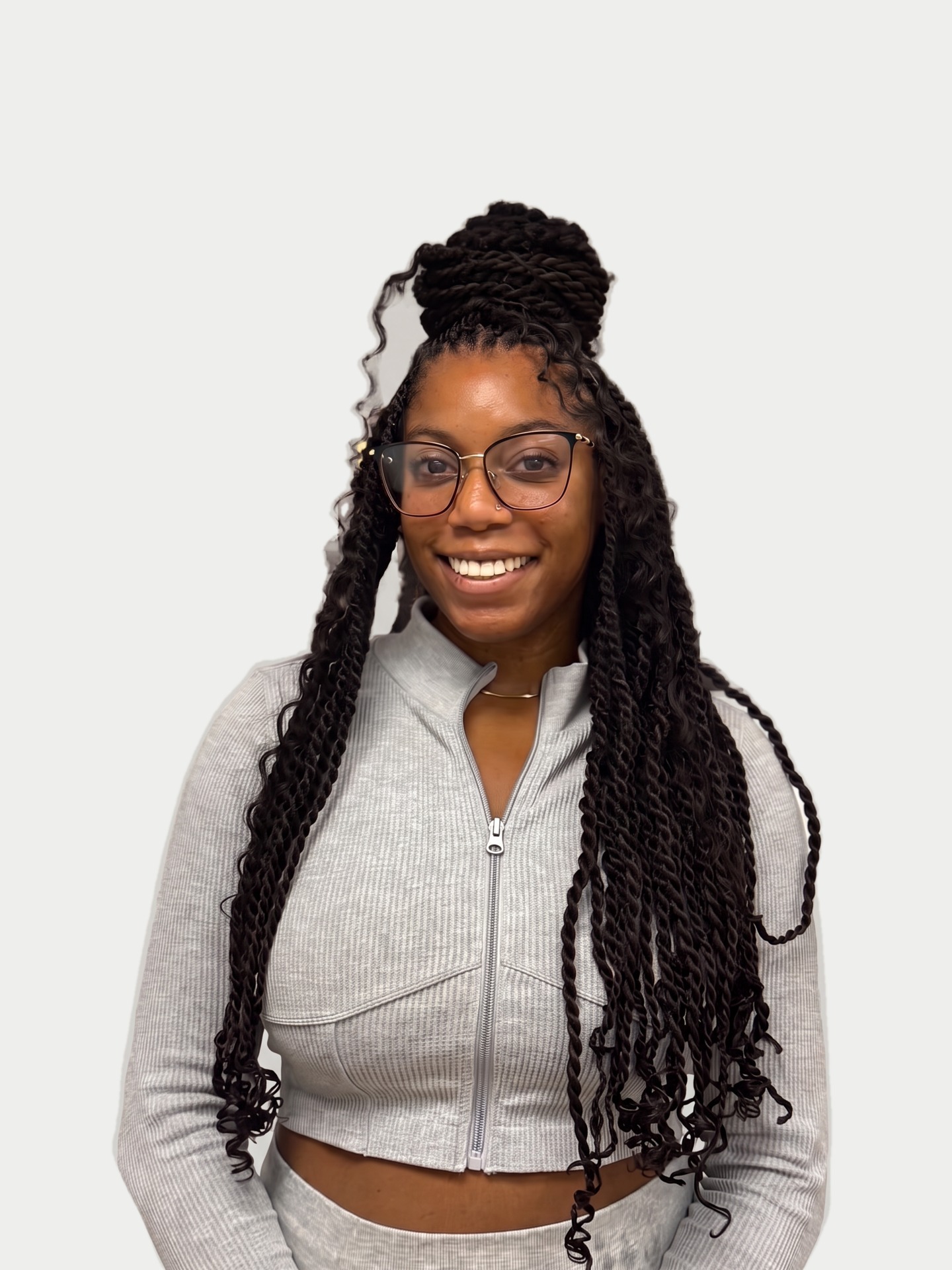 Smiling client with glasses and long black twists draped over both shoulders, on a very light gray background